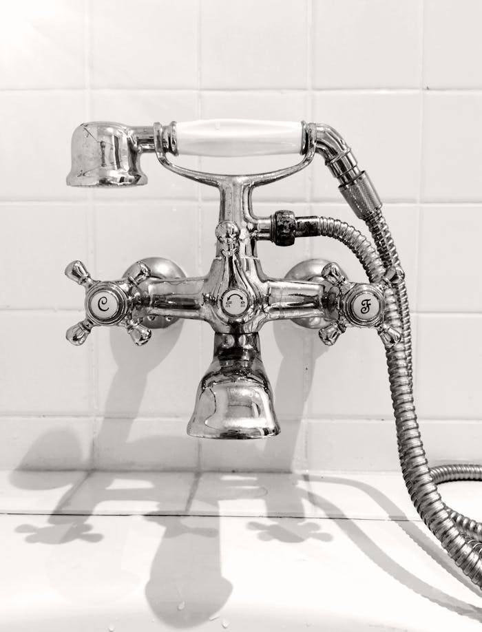 Elegant vintage chrome faucet in black and white, showcasing classic design and plumbing details.